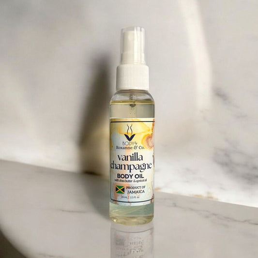 Bottle of Vanilla Champagne body oil on a marble surface with a neutral background
