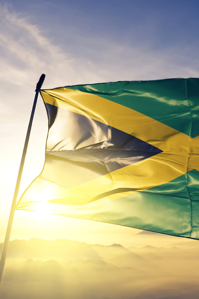Flag of Jamaica waving against a blue sky with sunlight